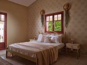 Een slaapkamer met een bed, twee nachtkastjes, een raam met uitzicht en een behang met patroon.