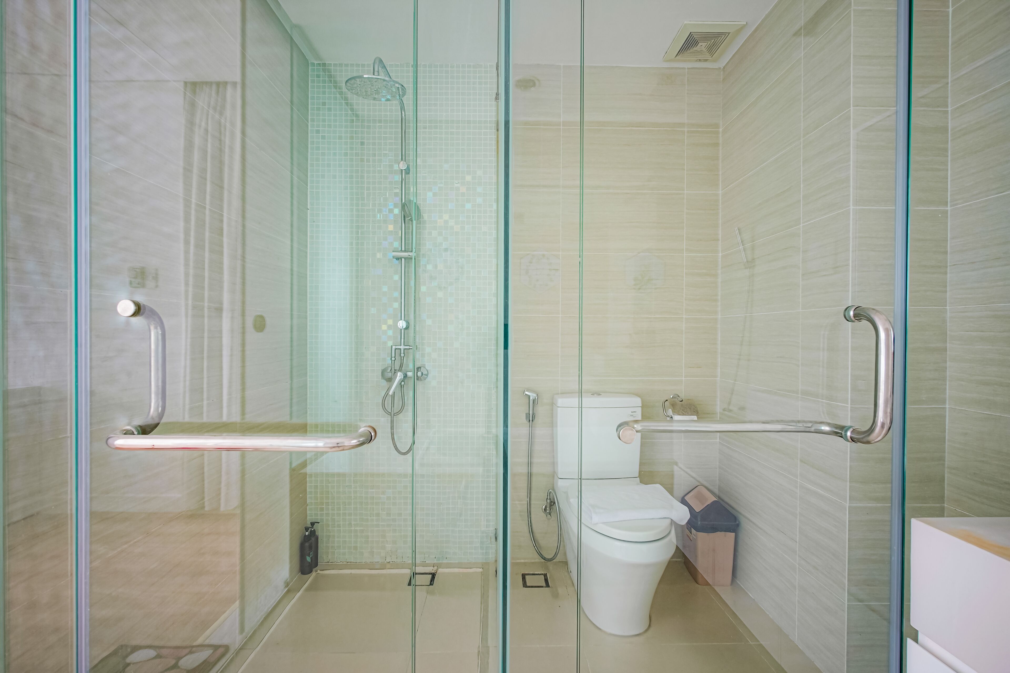 A modern bathroom with a glass shower enclosure, a toilet, and a bidet.