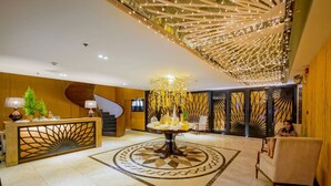 Un vestíbulo con mostrador de recepción, una mesa decorativa central, una escalera y una zona de estar.