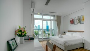 Habitación de hotel moderna con un ventanal grande, una cama, un escritorio y vistas del horizonte de la ciudad.
