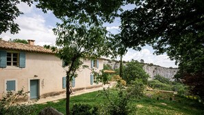 Una casa rústica con tejado de tejas, pared de piedra y un patio cubierto de césped.
