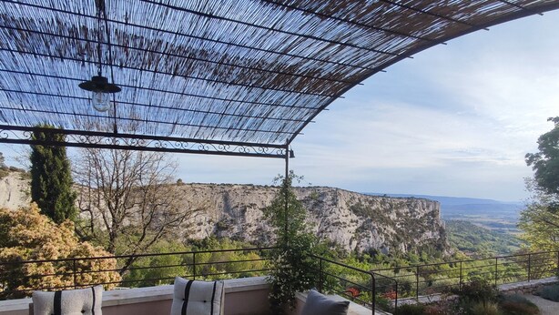 Una terraza con vistas a un acantilado, mobiliario exterior y una pérgola.