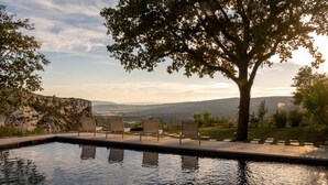Una piscina con cuatro sillas y un árbol al fondo.