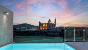 A rooftop pool with a view of a historic building at sunset. - Twilight Holiday Home (Għasri)