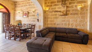 Une pièce aux murs de pierre, comprenant une table à manger, des chaises, un canapé et une cheminée.