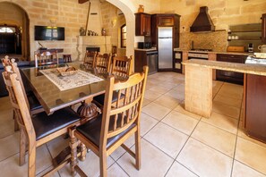A spacious kitchen with a dining area, stone walls, and modern appliances.