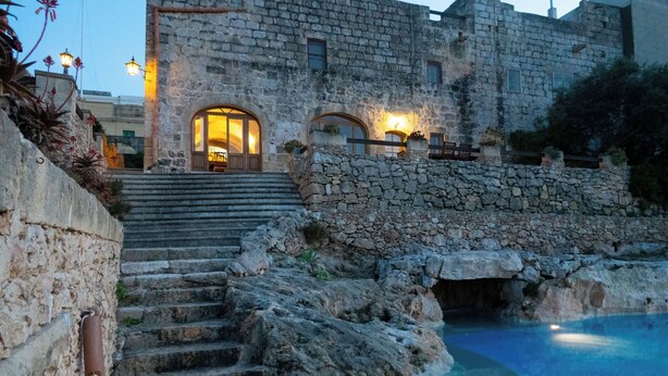 A stone building with a pool, steps leading to a door, and outdoor lighting. - Villeleynah Holiday Home (Gozo)