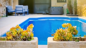 En swimmingpool med to plantekasser med gulgrønne planter i forgrunden.