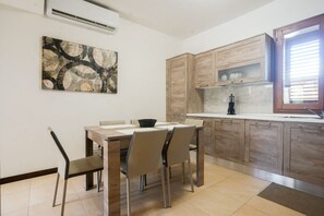A modern kitchen with wooden cabinets, a marble countertop, and a dining area with a table and chairs.