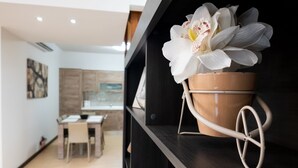 A modern kitchen with wooden cabinets, a dining table with chairs, and a potted orchid on a shelf. - GetawayNpetto Holiday Home (Ghajnsielem)