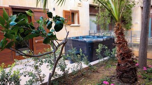 A courtyard with a hot tub, palm tree, and various plants. - GetawayNpetto Holiday Home (Ghajnsielem)