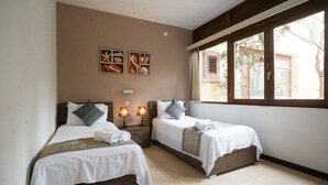 A hotel room with two beds, a window with a view, and wall art. - GetawayNpetto Holiday Home (Ghajnsielem)