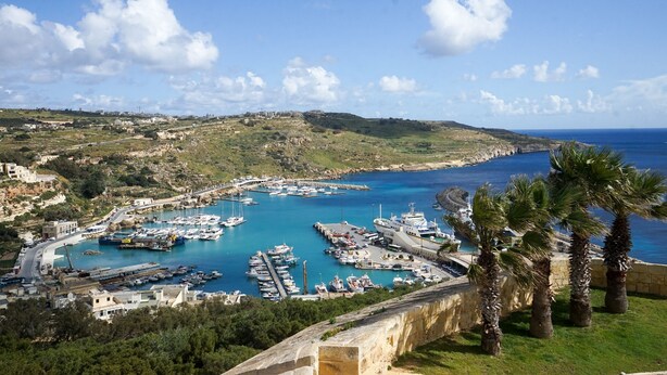 A coastal marina with boats docked, a large ship, and a view of the sea and hills. - GetawayNpetto Holiday Home (Ghajnsielem)