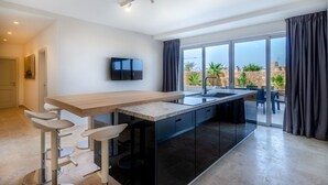 A modern kitchen with a bar area, large windows, and a view of the outdoors. - Hygge Holiday Home (Ix-Xagħra)