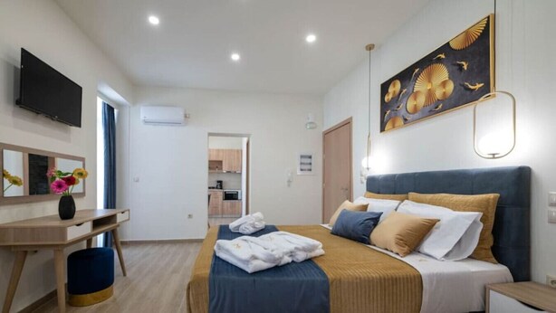 Ein Schlafzimmer mit Bett, Nachttisch, Fernseher und einem Bild an der Wand.
