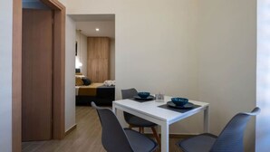 Ein kleines Zimmer mit einem Bett, einem Tisch mit Stühlen und einer Tür zu einem anderen Raum.