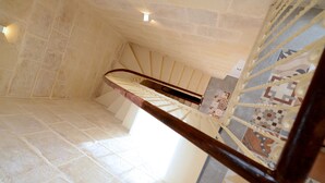 Una escalera de piedra con barandilla de madera y baldosas de suelo con diseño.