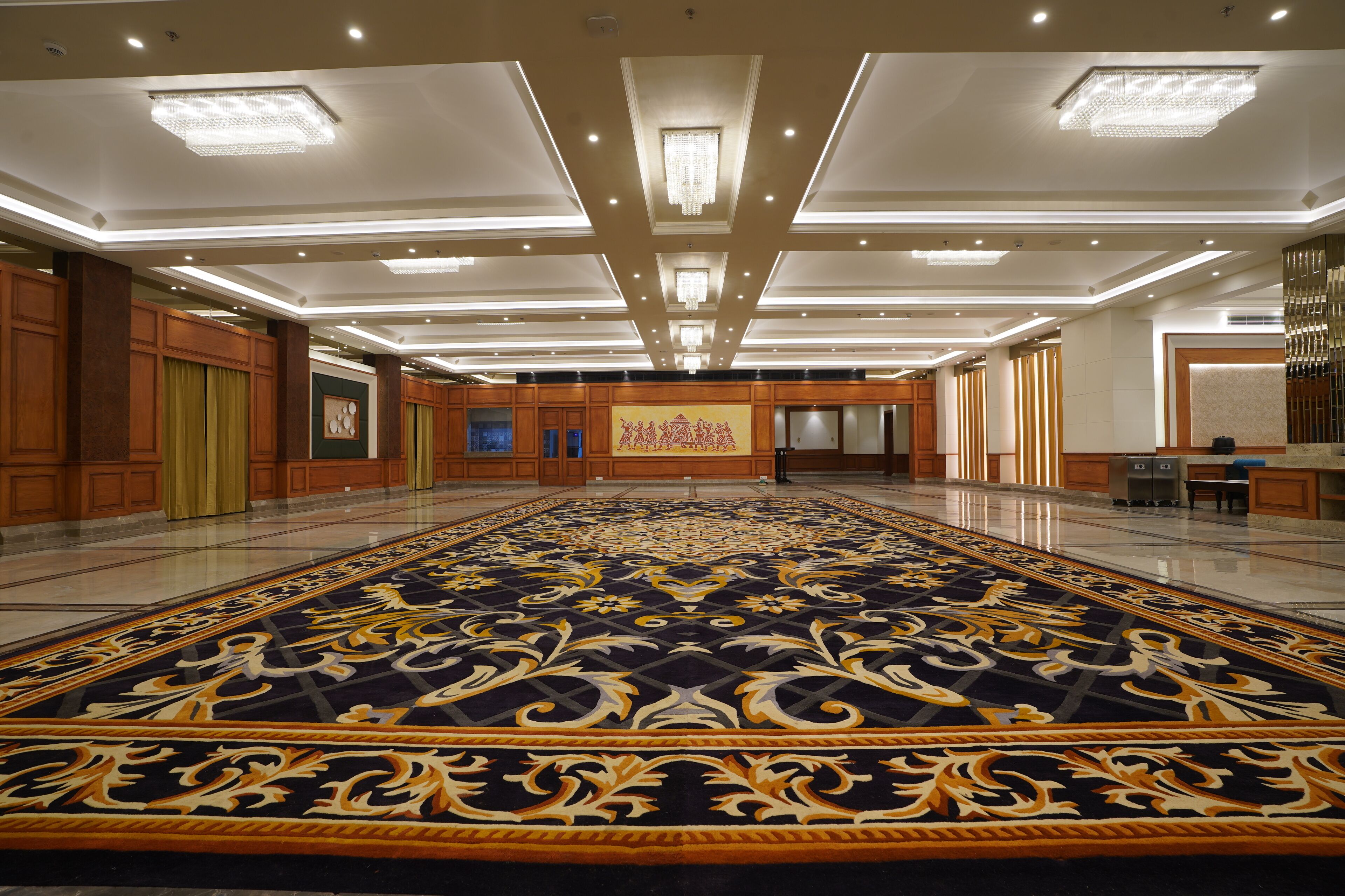 Un amplio vestíbulo de hotel con una alfombra grande y elaborada, paneles de madera y un mostrador de recepción.