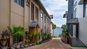 A pathway flanked by buildings with a view of a mountainous landscape. - WelcomHeritage Parv Vilas Resort & Spa (Solan)