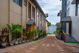 A pathway flanked by buildings with a view of a mountainous landscape.