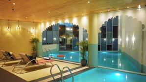 An indoor swimming pool with lounge chairs and potted plants. - WelcomHeritage Parv Vilas Resort & Spa (Solan)