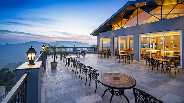 A terrace with outdoor seating and a view of the mountains. - WelcomHeritage Parv Vilas Resort & Spa (Solan)