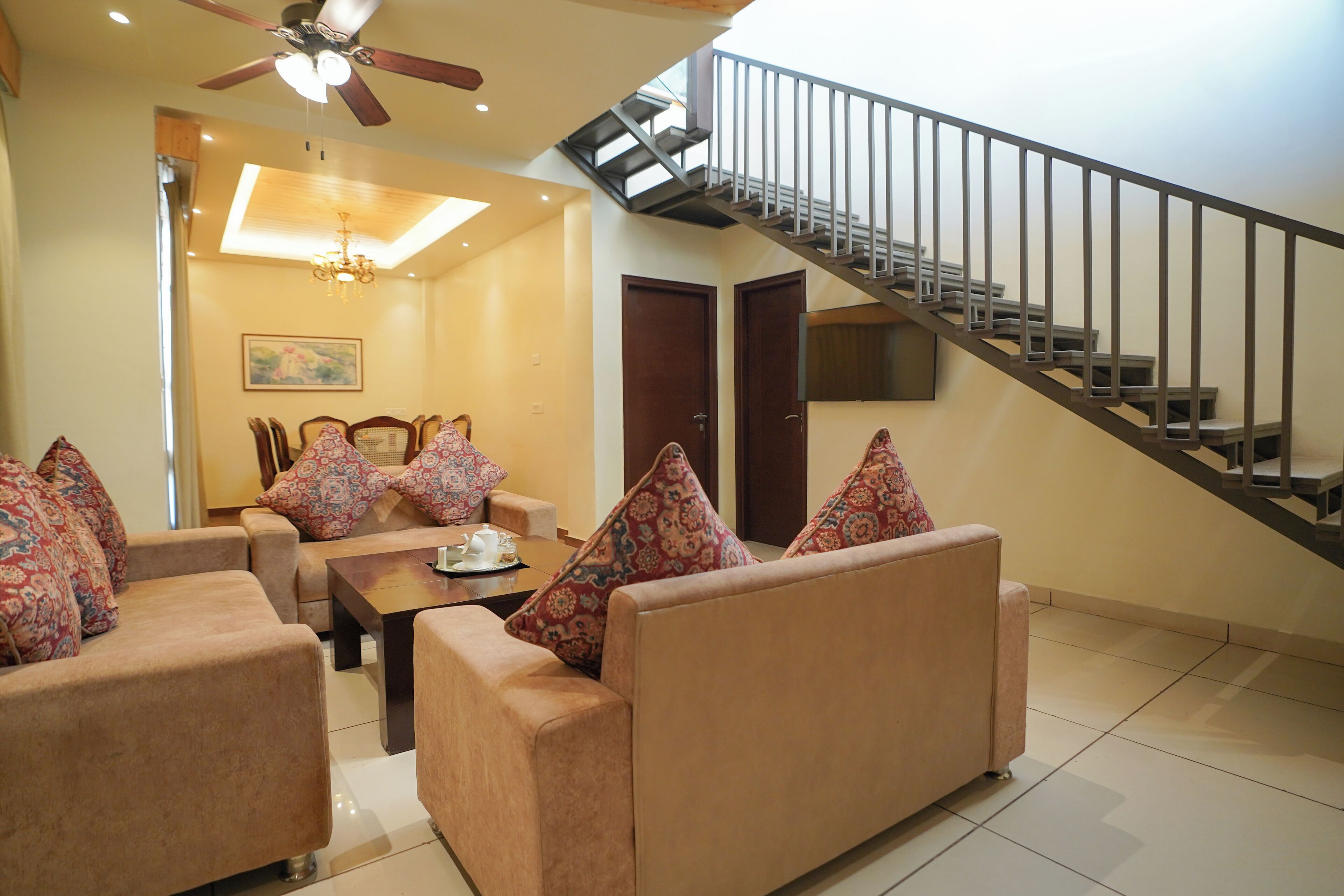 A living room with a sofa set, a coffee table, and a staircase.