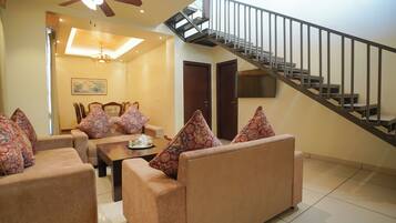 A living room with a sofa set, a coffee table, and a staircase.