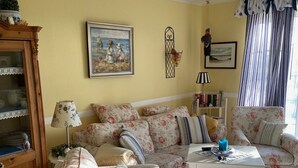 A living room with floral-patterned sofas, a wooden cabinet, and a tiled floor. - Vacation home in quiet, relaxing surroundings Zingst / Müggenburg (Zingst)
