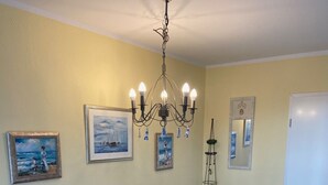 A dining area with a wooden table, blue chairs, and a chandelier. - Vacation home in quiet, relaxing surroundings Zingst / Müggenburg (Zingst)