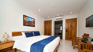 Une chambre avec un grand lit, une armoire en bois et un coin repas comprenant des chaises et une table.