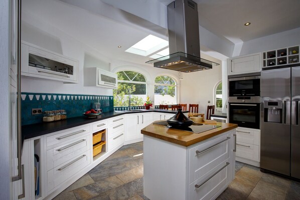 A modern kitchen with white cabinetry, a central island, and a built-in oven.