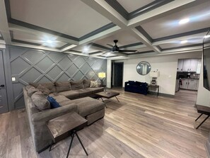 A modern living room with a sectional sofa, a coffee table, and a ceiling fan.