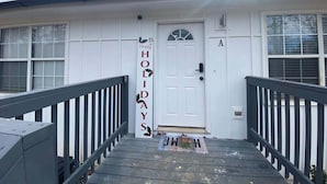 A house with a white exterior, a front door, and a small porch with a black railing.