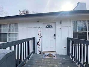 A house with a white exterior, a front door, and a small porch with a black railing.