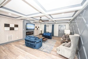 Ein modernes Wohnzimmer mit Flachbildfernseher, blau-weißen Möbeln, Kamin und Deckenventilator.