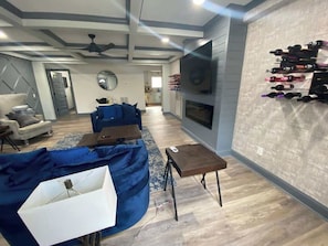 A living room with a sofa, a coffee table, a TV, and a wine rack.