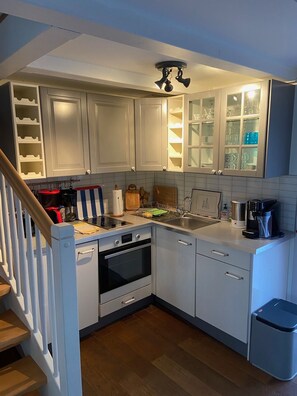 A compact kitchen with white cabinets, a built-in oven, a sink, and a coffee maker. - A quiet outbuilding in Zingst / Müggenburg (Zingst)