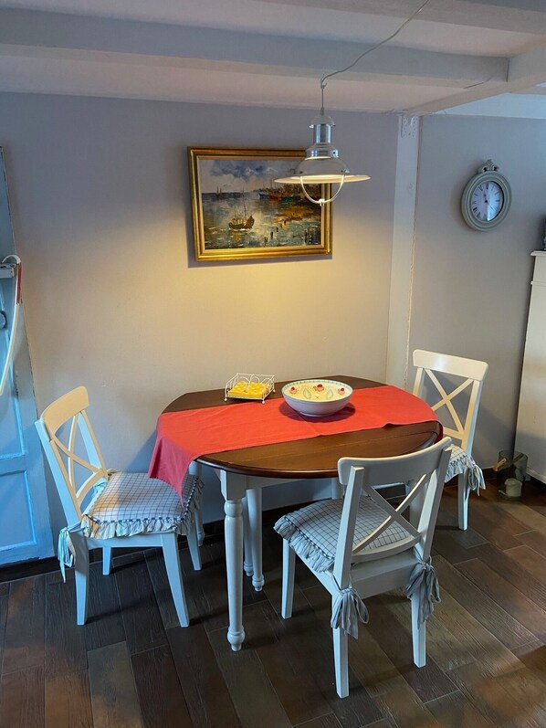 A dining area with a round table, four chairs, a red tablecloth, a bowl, and a painting on the wall. - A quiet outbuilding in Zingst / Müggenburg (Zingst)