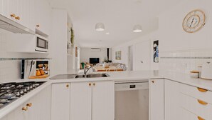 Een moderne keuken met witte kasten, roestvrijstalen apparatuur en een centraal eiland.
