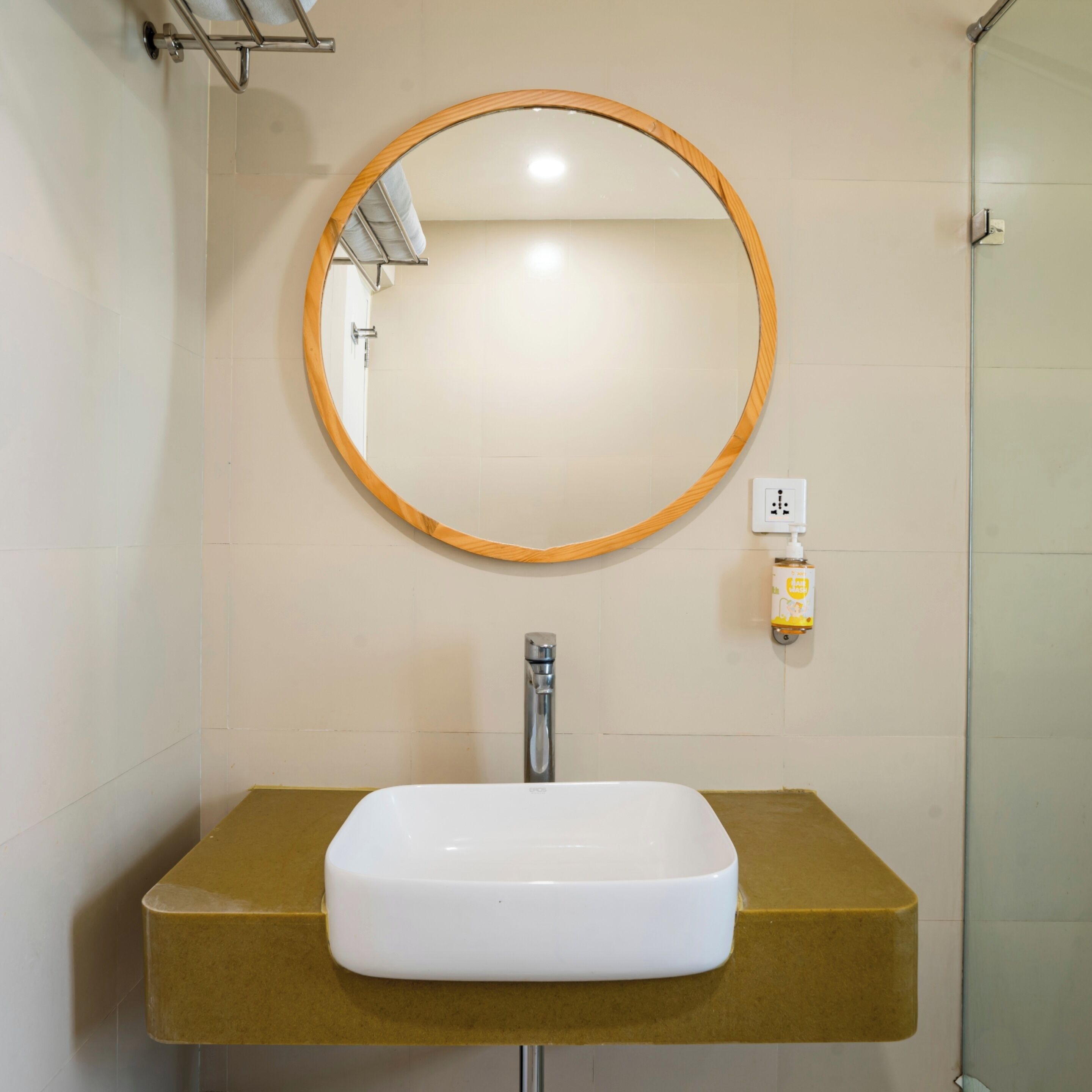 A bathroom with a white sink, a wooden-framed mirror, and a hand sanitizer dispenser on the wall.