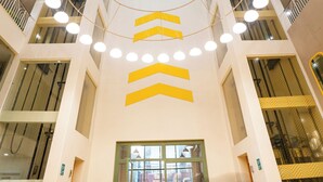 A modern atrium with a central spiral staircase, multiple floors, and a glass elevator shaft. - Bloom Hotel - Jammu (Jammu)