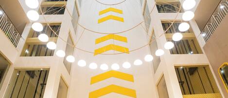 A modern atrium with a central spiral staircase, multiple floors, and a glass elevator shaft.