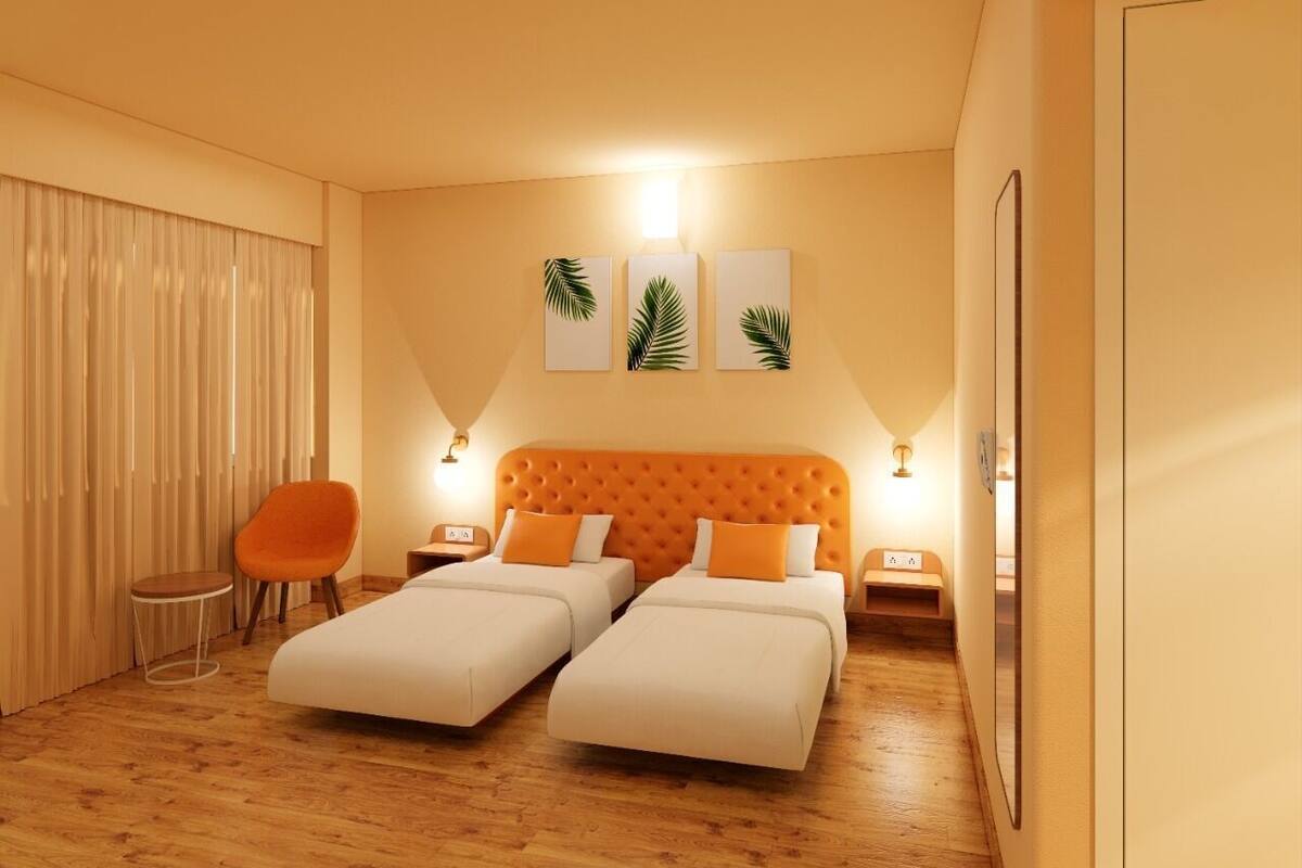 A hotel room with two beds, a chair, a nightstand, and a wall-mounted light.