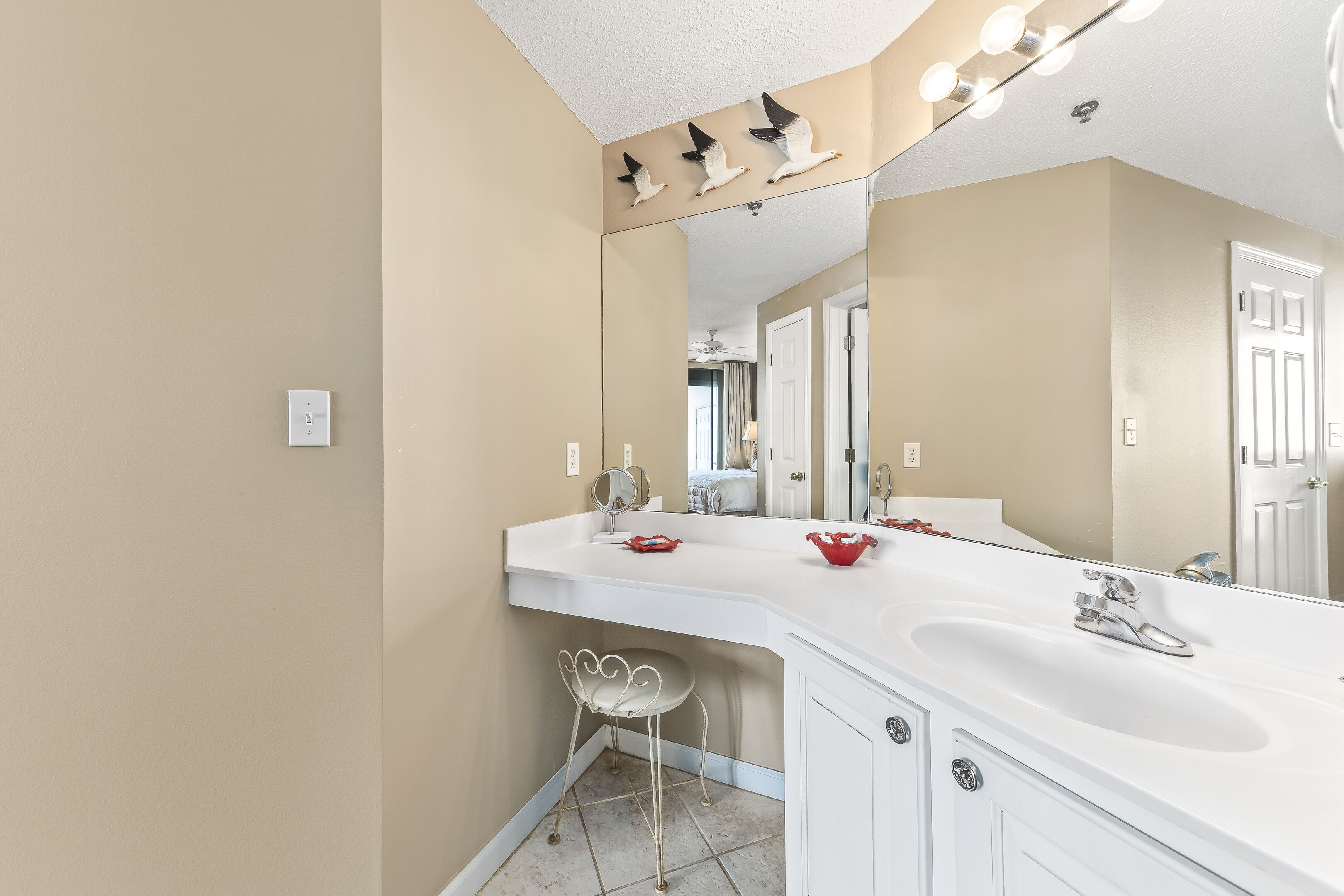 A bathroom with a white vanity, a large mirror, and a light fixture above the mirror.