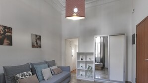 Un saló modern amb un sofà gris, un moble d'estanteries blanc i un armari amb portes corredisses.