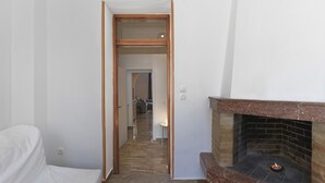 Quarto com lareira, um sofá branco e um corredor que leva a outro quarto.