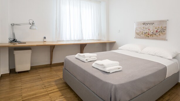 Un dormitorio ordenado con una cama, un escritorio y una ventana.