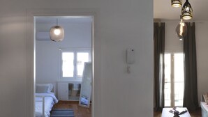Ett sovrum med en säng, ett nattduksbord och ett fönster. En hall leder vidare till en matplats med ett bord och stolar.