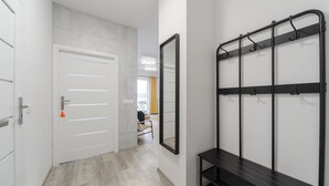 A hallway with a white door, a mirror, and a black bench with hooks. - Lumina apart near Cinema Museum (Lodz)